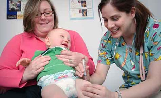 photo of mom holding a baby when getting a vaccine from doctor
